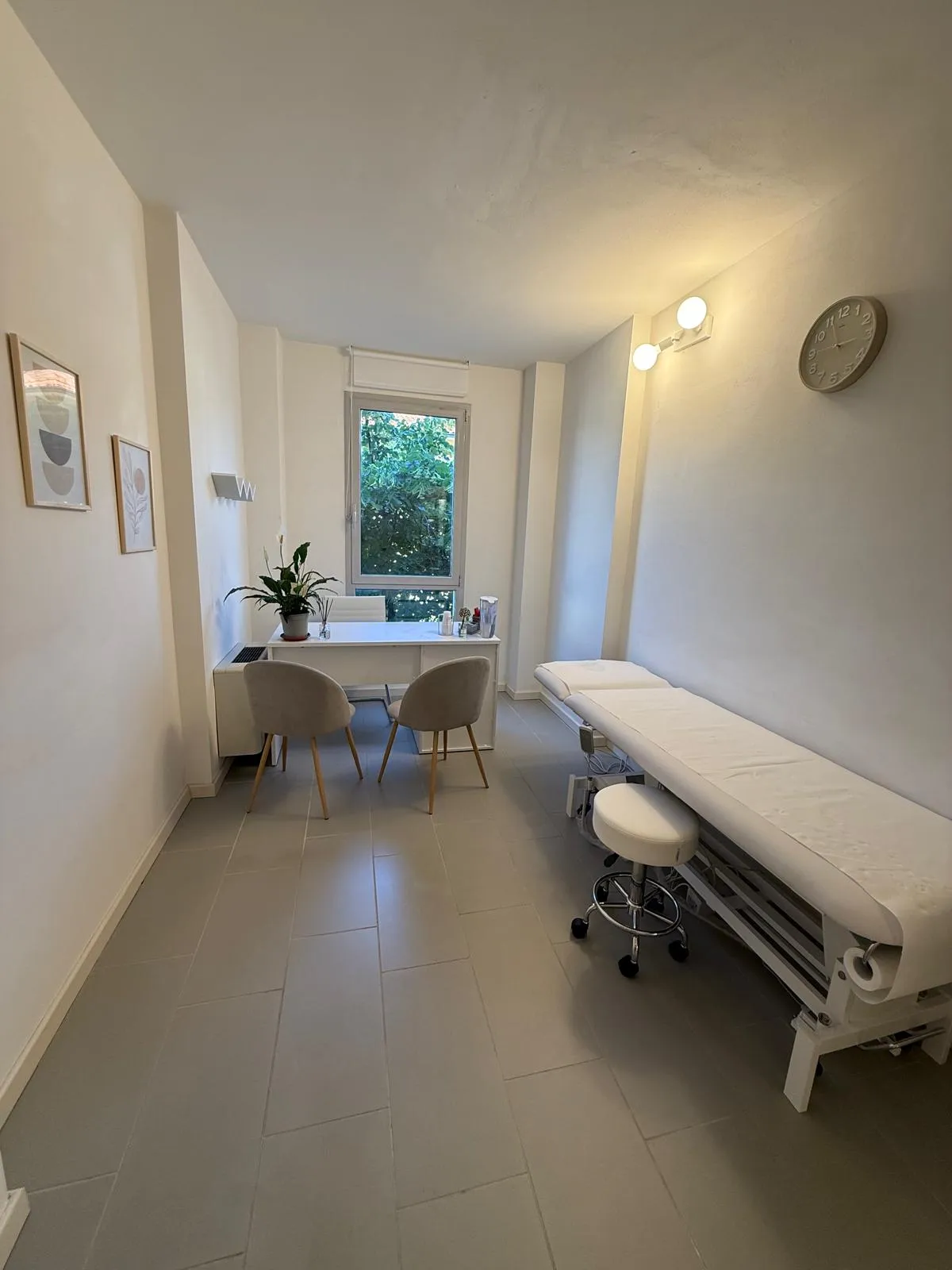 Stanza di trattamento con lettino, scrivania bianca e finestra sul giardino