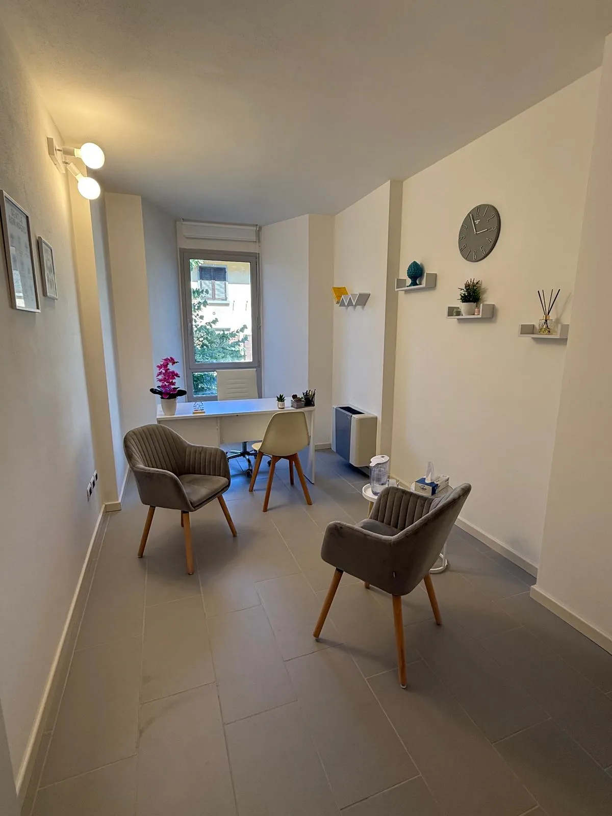 Sala di consulenza raccolta, poltrone in velluto neutro, luce calda